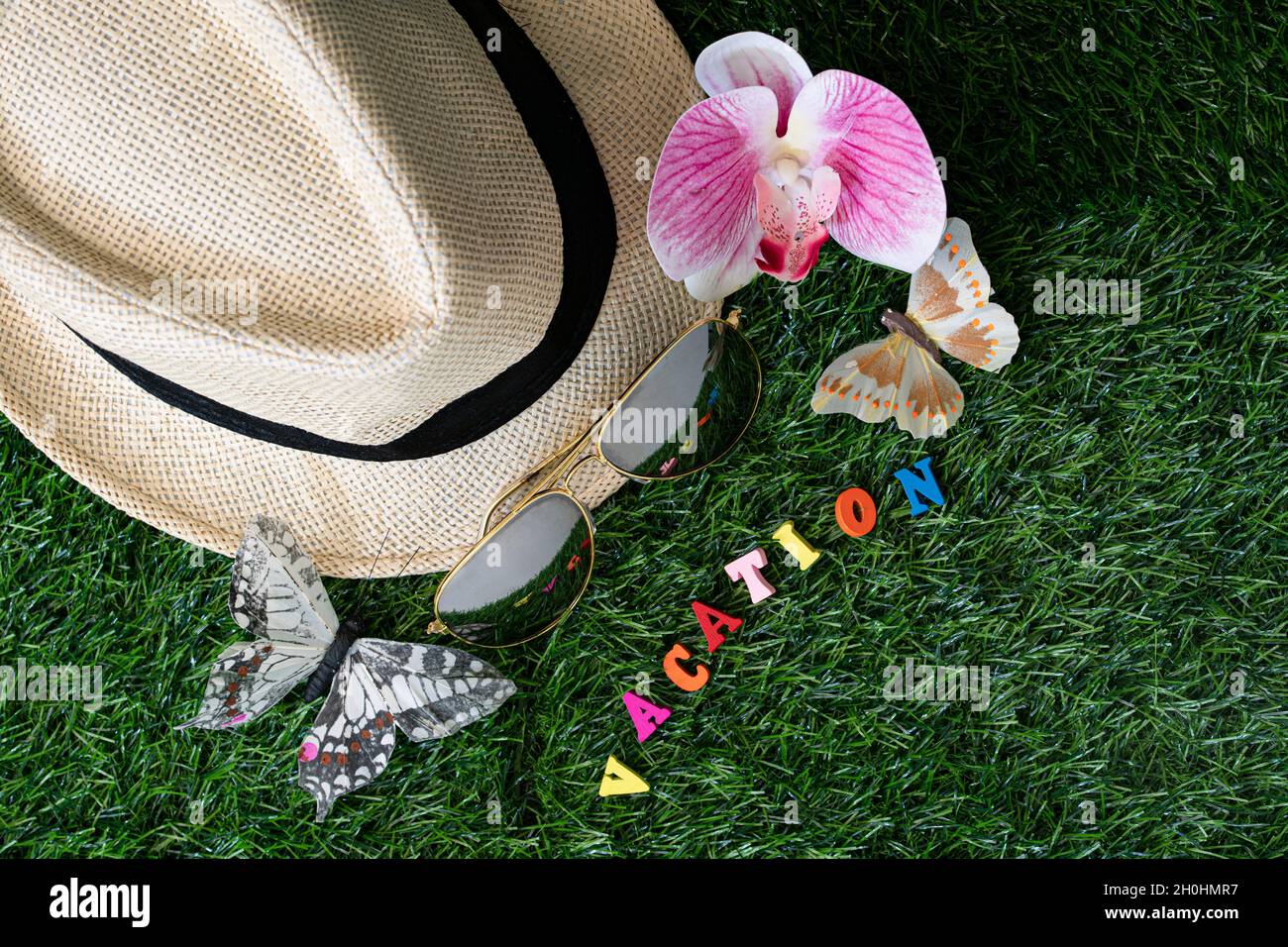 Concept de vacances.Disposition de chapeau de paille, faux papillon, orchidée, lunettes de soleil et alphabet de bois avec texte VACANCES. Banque D'Images