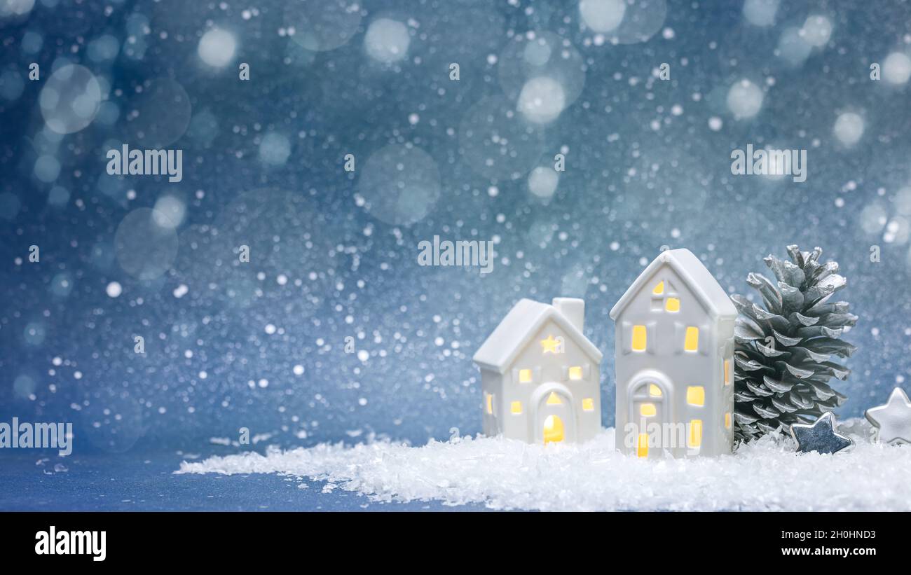 décorations de vacances d'hiver. maisons de jouets illuminées avec cône de sapin et étoiles argentées sur fond bleu flou. Banque D'Images