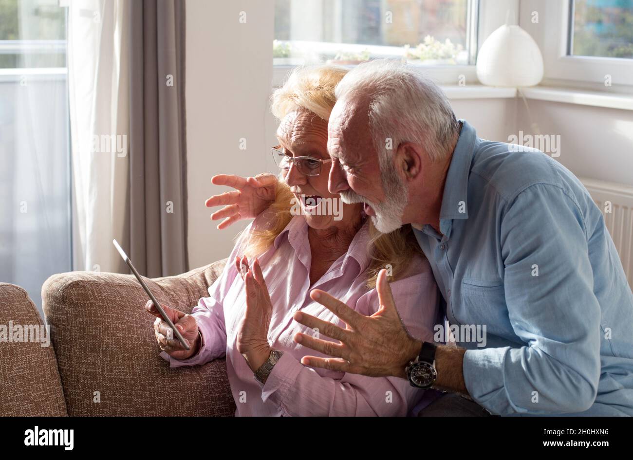 Couple âgé utilisant une tablette pour communiquer avec la famille Banque D'Images