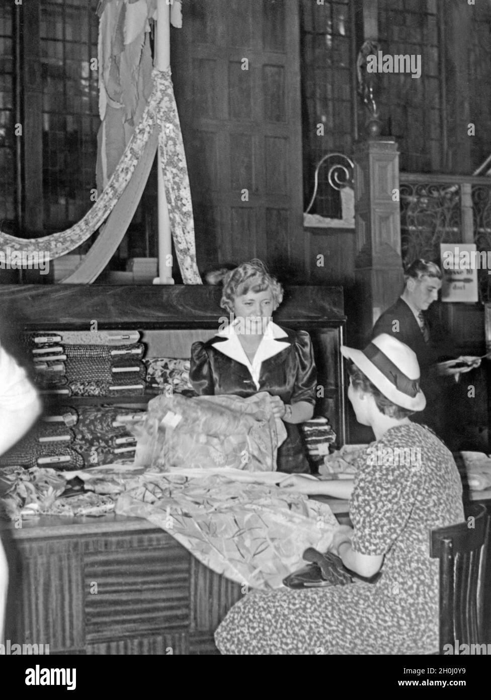 Une vendeuse montre à un client différents tissus dans un magasin à Berlin.[traduction automatique] Banque D'Images