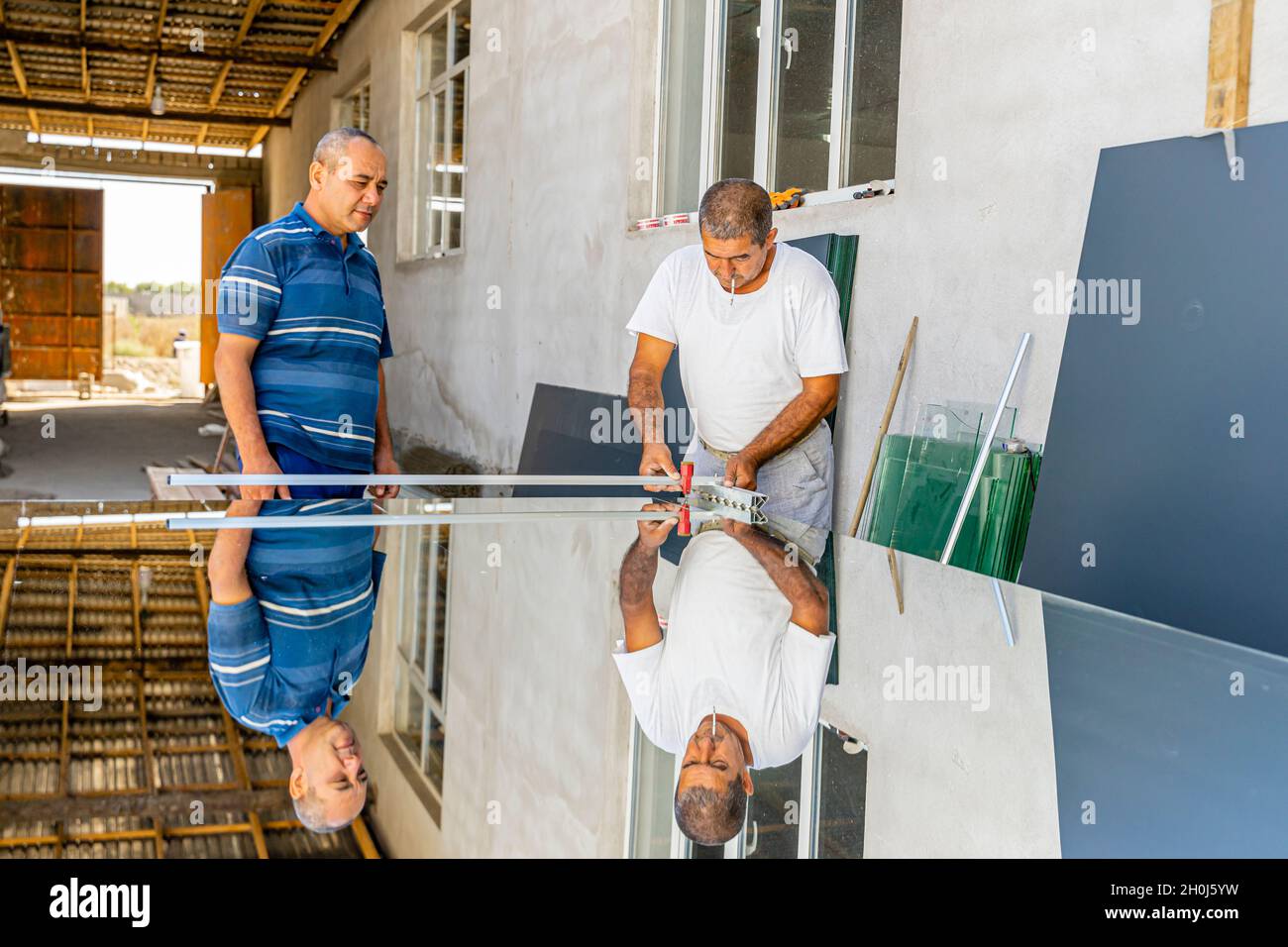 Un homme coupant verre de miroir avec coupe-verre à utiliser dans la production locale de meubles Banque D'Images