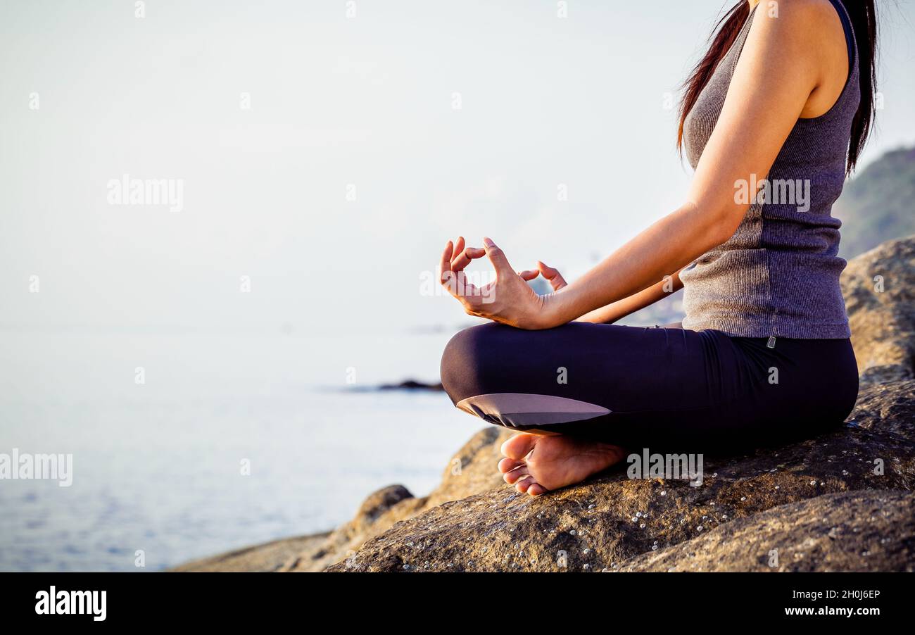 La femme méditant dans une pose de yoga sur la plage tropicale. Femme méditant surplombant le magnifique lever du soleil. Esprit Sain de corps et d'esprit concept. Banque D'Images