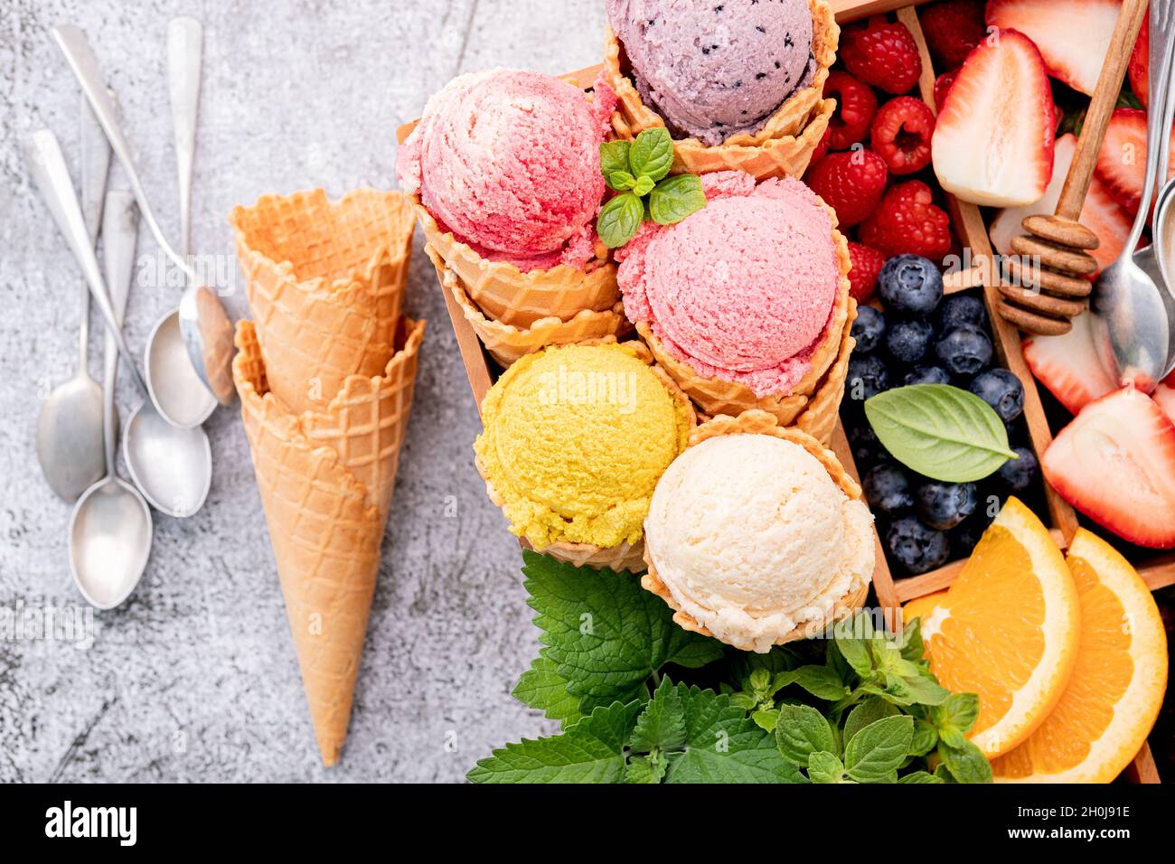 Divers de saveur de crème glacée dans des cônes avec des baies en boîte de bois sur fond de béton . Concept de menu été et sucré. Banque D'Images