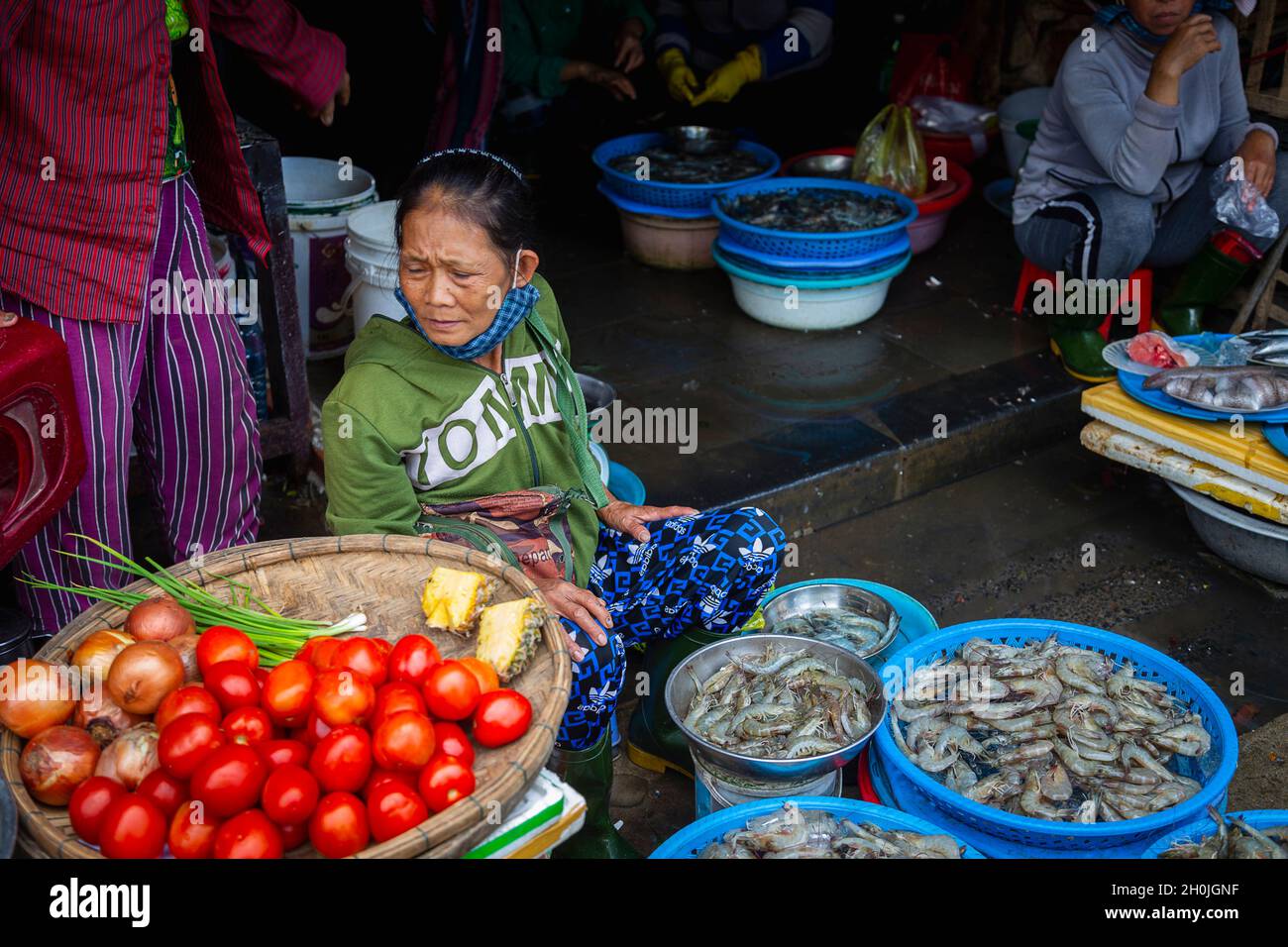 Une dame se trouve devant son stand vendant des crevettes et des légumes au marché Hoi an. Banque D'Images
