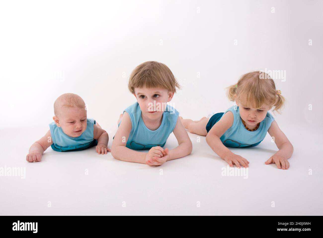 trois petits enfants couchés les uns à côté des autres en position de décubitus ventral Banque D'Images