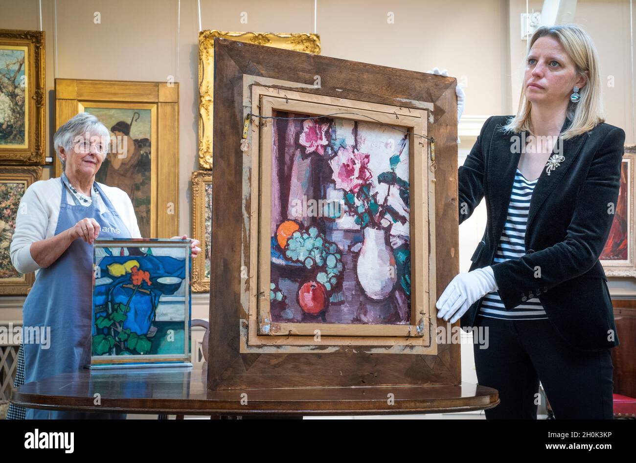 May Matthews (à droite) de Bonhams montre 'la vie de till avec des roses et des fruits' par Samual John Paploe qui est à l'inverse de la toile double-face 'la vie de till avec Geranium' (vers 1913) comme vu dans un miroir tenu par Lorna MacGregor (à gauche) lors d'un aperçu de la prochaine vente écossaise chezBonhams à Édimbourg.Les articles de la vente, qui comprennent également des œuvres d'autres artistes écossais Jack Vettriano et James Paterson, sont vendus à l'aide des organismes de bienfaisance Amnesty International et médecins sans frontières.Date de la photo: Mercredi 13 octobre 2021. Banque D'Images