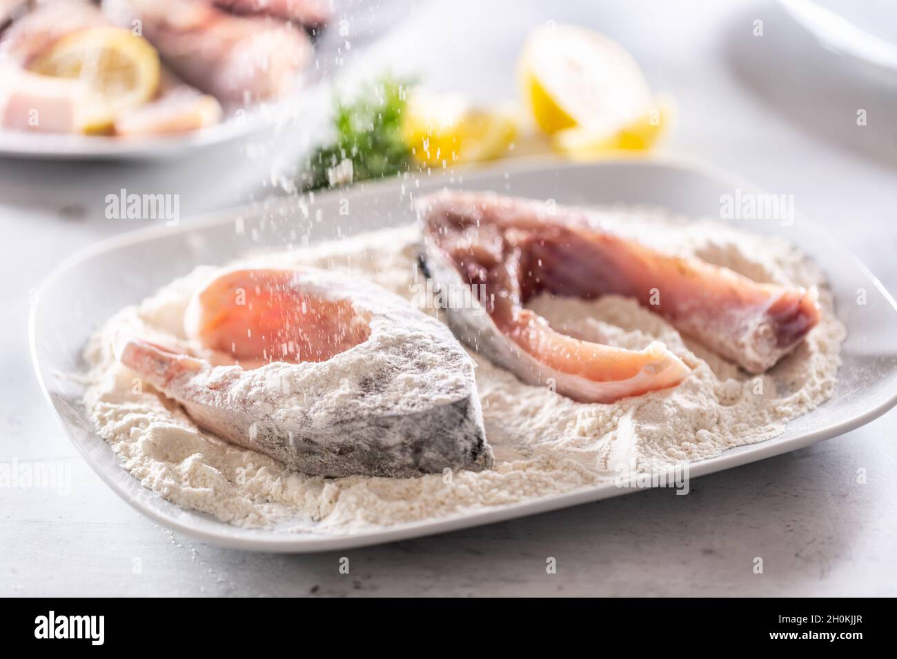 Préparation du poisson frais avant la friture en l'emballant dans la farine. Banque D'Images