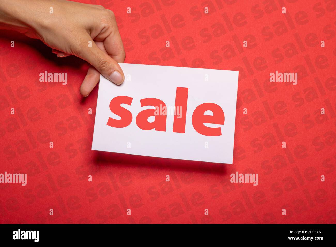 main féminine tient un morceau de papier avec l'inscription vente sur fond rouge fort carton avec la vente écrite sur pour promouvoir des ventes spéciales Banque D'Images