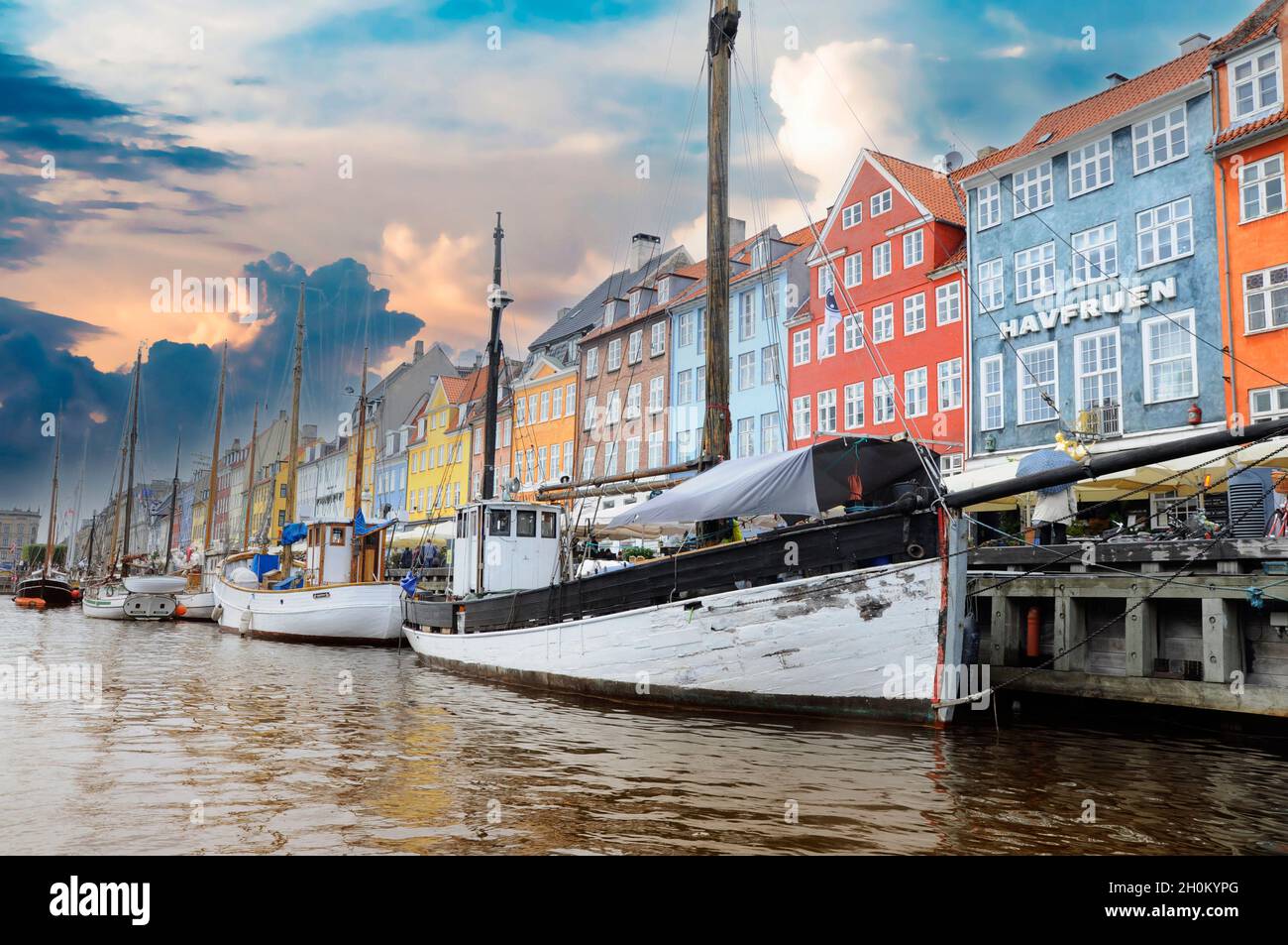 Canal de Nyhavn avec des navires au coucher du soleil sous un ciel partiellement nuageux Copenhague, Danemark. Banque D'Images