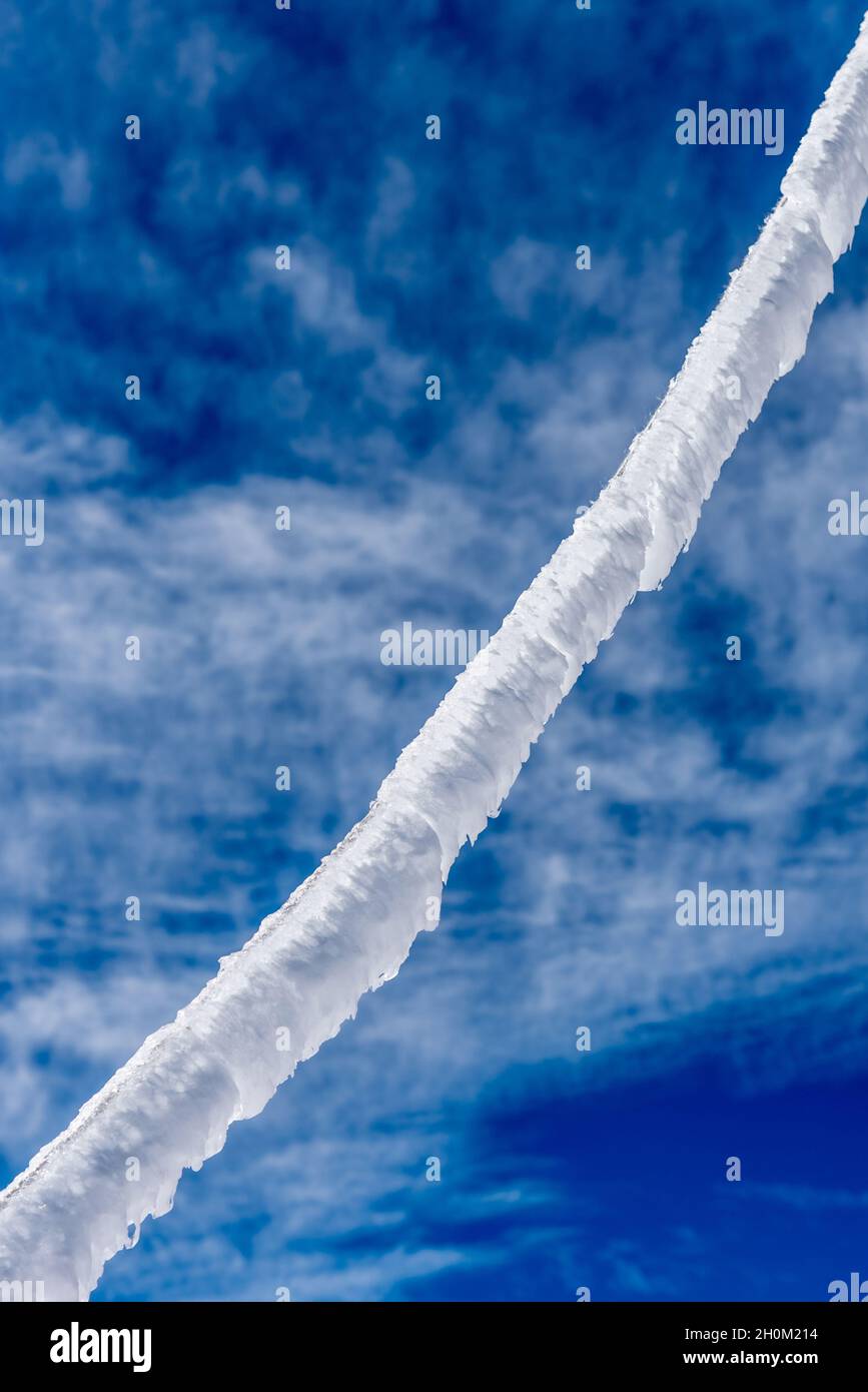 Un givre recouvrant une corde un jour d'hiver froid sur un fond de ciel bleu avec des nuages Banque D'Images
