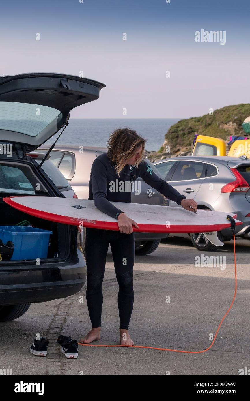 Un surfeur qui cirage sa planche de surf dans un parking de Little Fistral à Newquay, en Cornouailles. Banque D'Images
