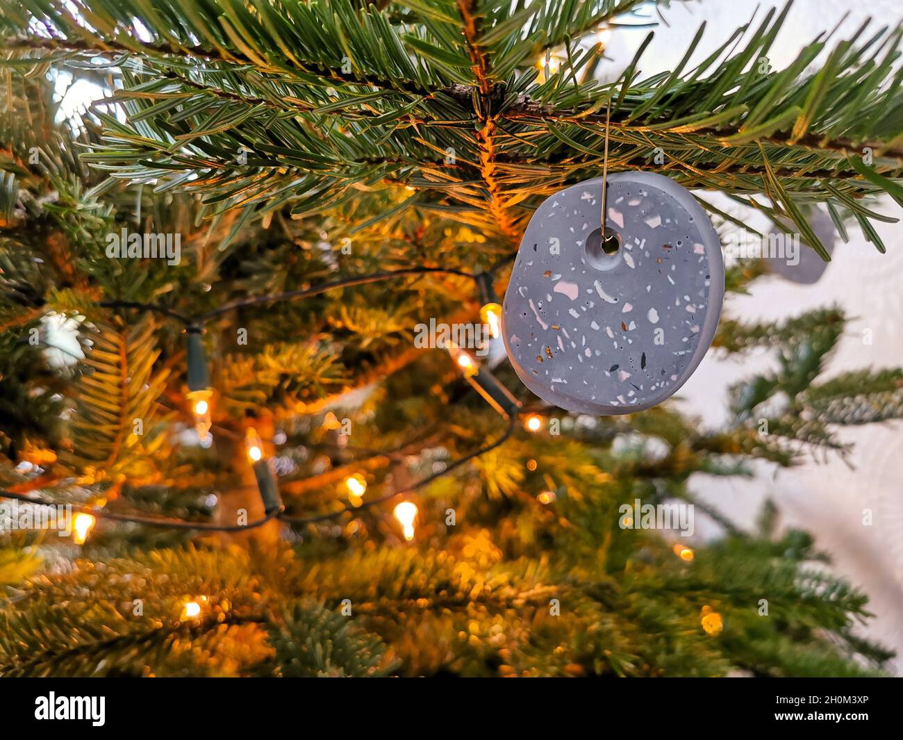 Boule de noël moderne en terrazzo artisanale accrochée dans l'arbre de noël Banque D'Images