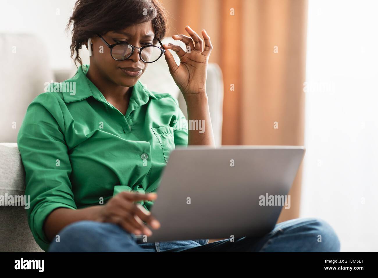 Femme noire avec une mauvaise vue utilisant un ordinateur portable portant des lunettes de vue intérieur Banque D'Images