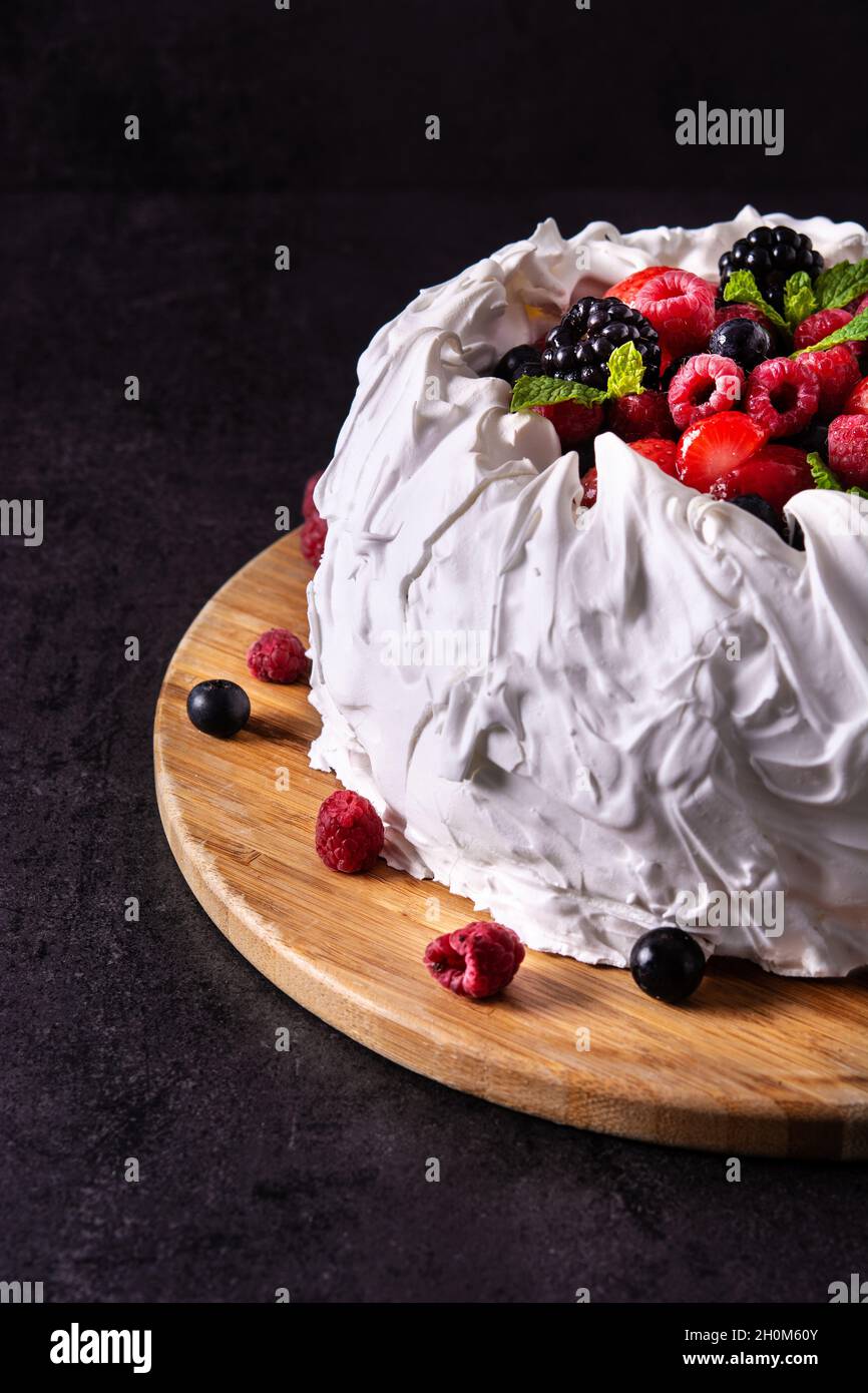 Délicieux gâteau Pavlova avec surfinition meringue et baies fraîches sur noir Banque D'Images
