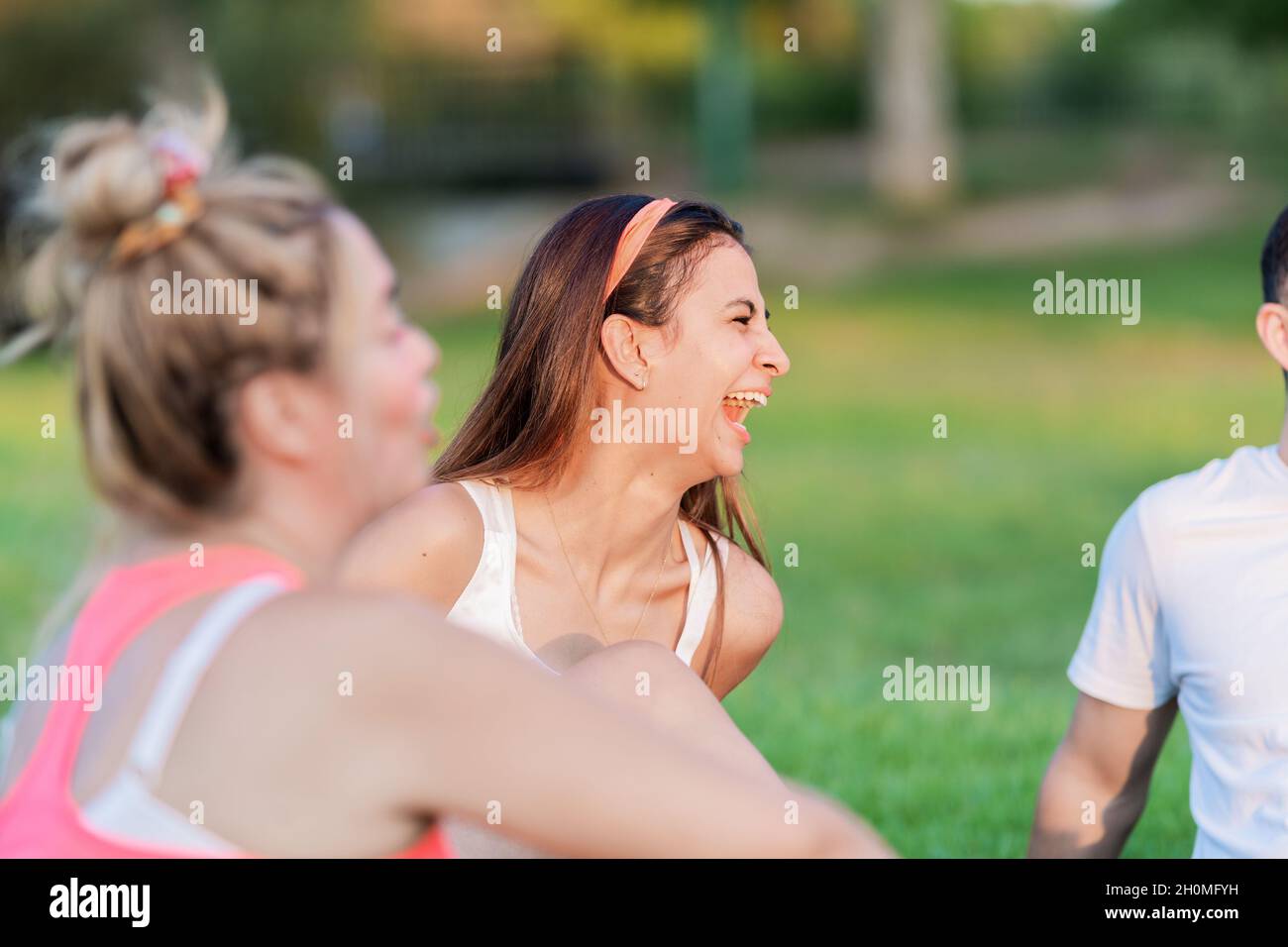 Attention sélective sur une femme qui rit en s'asseyant dans un parc avec quelques amis Banque D'Images