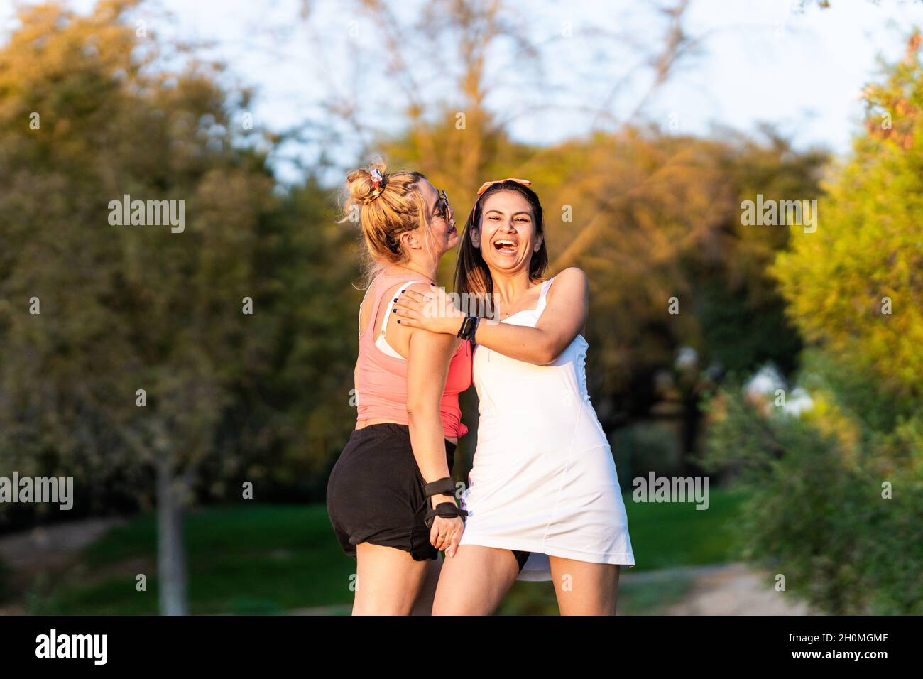 Deux amis rient en se tenant dans un parc Banque D'Images