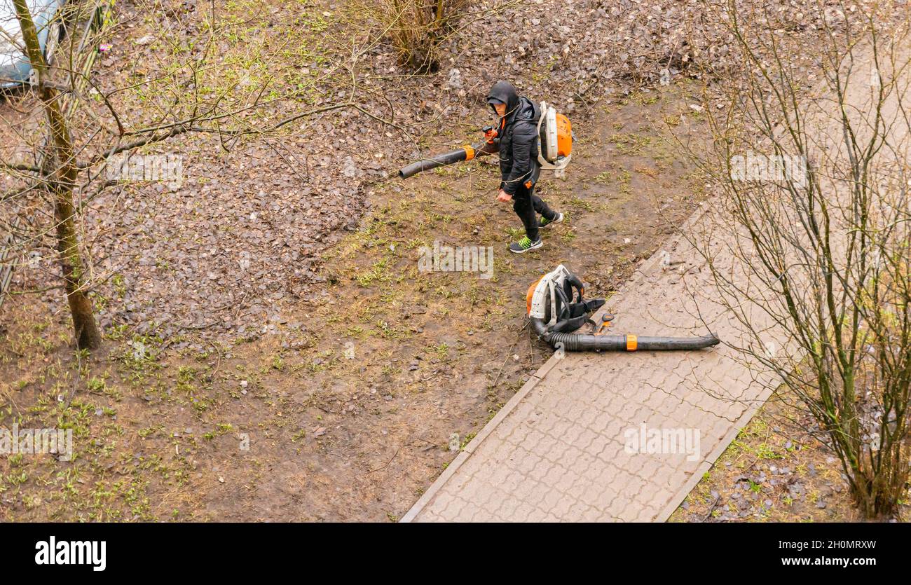 Un ouvrier nettoie la cour résidentielle avec un souffleur de feuilles après les travaux d'arbres, St Petesrburg, Russie Banque D'Images