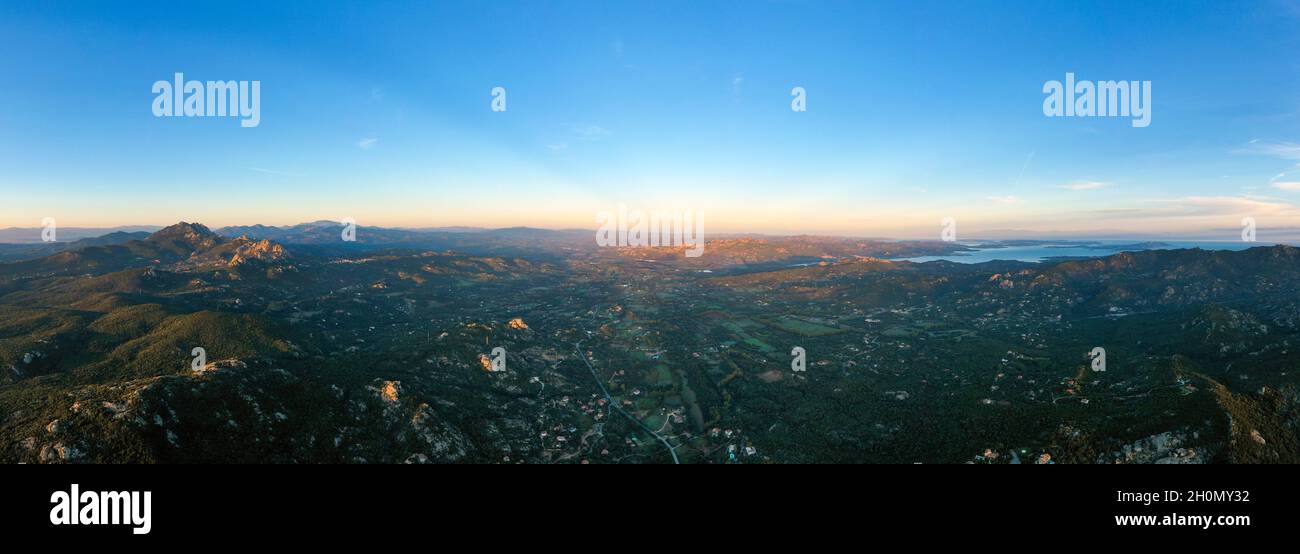 Vue d'en haut, prise de vue aérienne, vue panoramique sur une côte verte baignée par une eau calme pendant un beau lever de soleil.Sardaigne, Italie. Banque D'Images