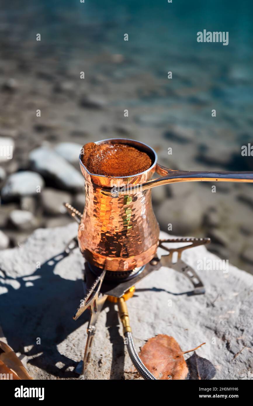 Cuivre Cézve pour le café en automne camping lac dans les montagnes.Préparation du café sur cuisinière à gaz concept de camping extérieur Banque D'Images