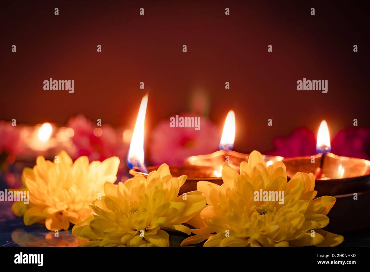 Bonne Diwali.Symboles traditionnels du festival indien de la lumière.Lampes à huile de diya et fleurs brûlantes sur fond rouge.Copier l'espace. Banque D'Images