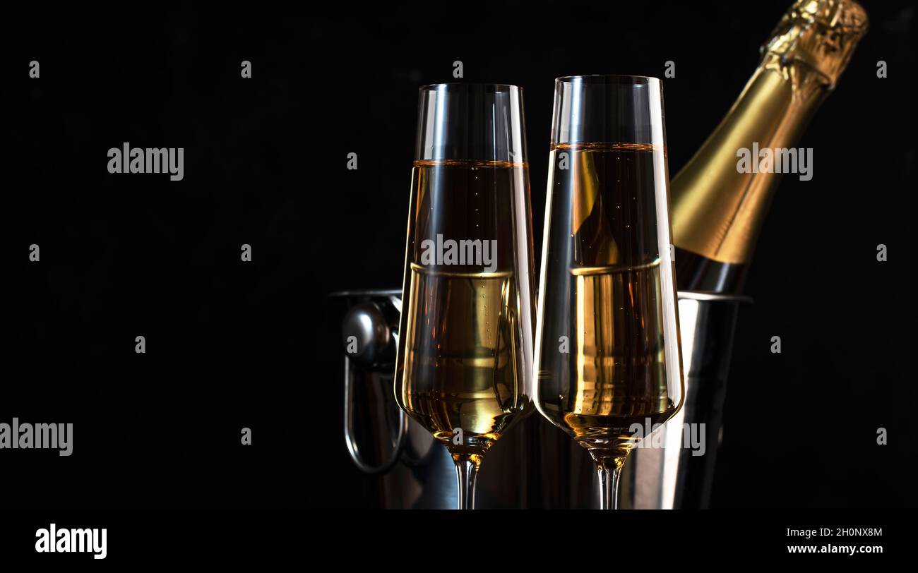 Deux verres à champagne et une bouteille dans un seau sur fond noir.Bonne année ou joyeux Noël Banque D'Images