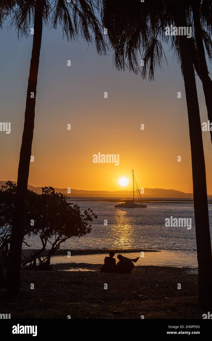 Couple adulte se détendant et regardant le coucher de soleil sur l'eau. Banque D'Images