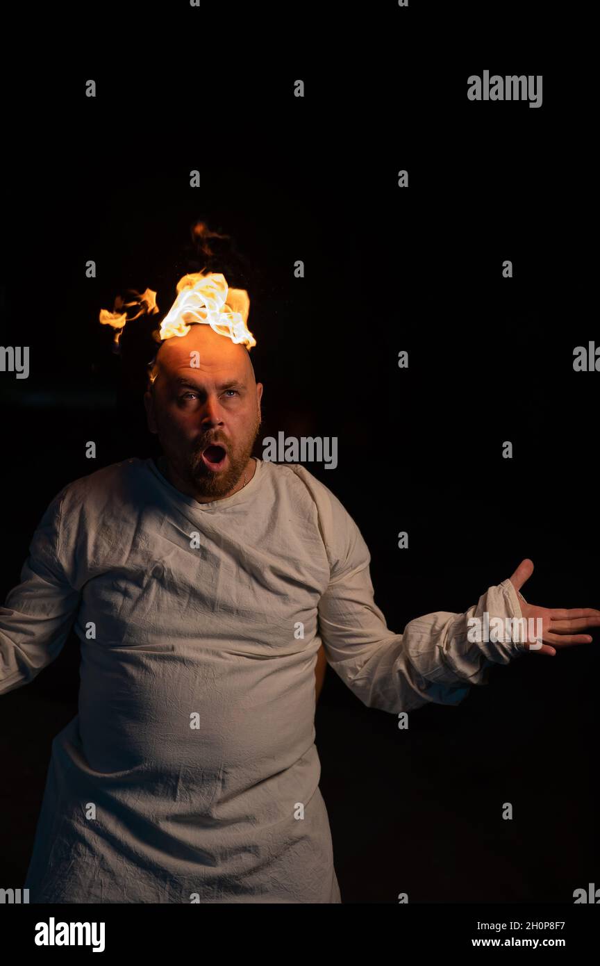 Homme chauve dans un blouson avec une tête brûlante sur un fond sombre. Banque D'Images