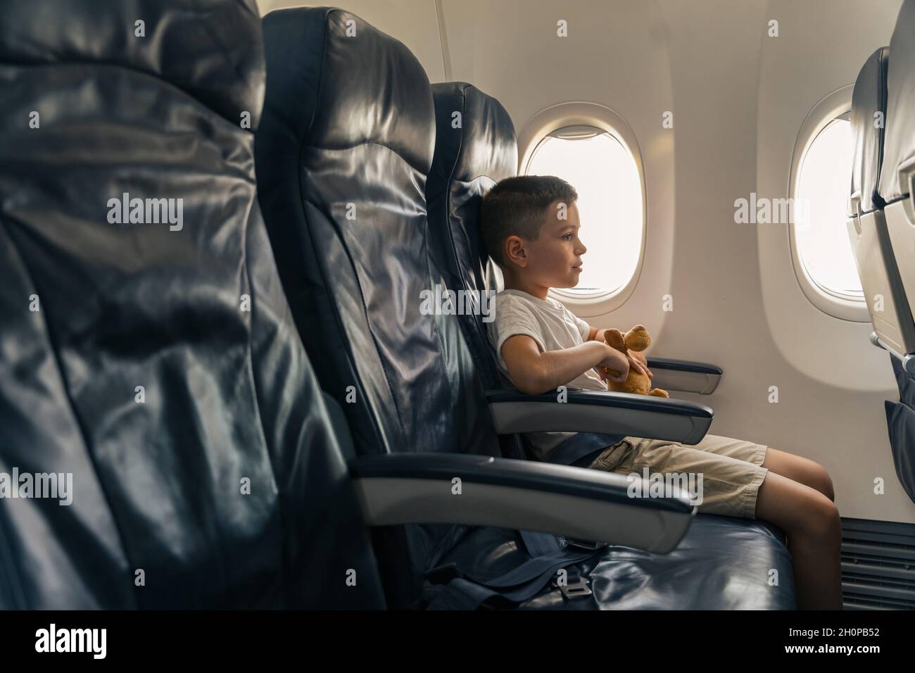 Enfant avec jouet préféré assis sur le siège d'avion Banque D'Images