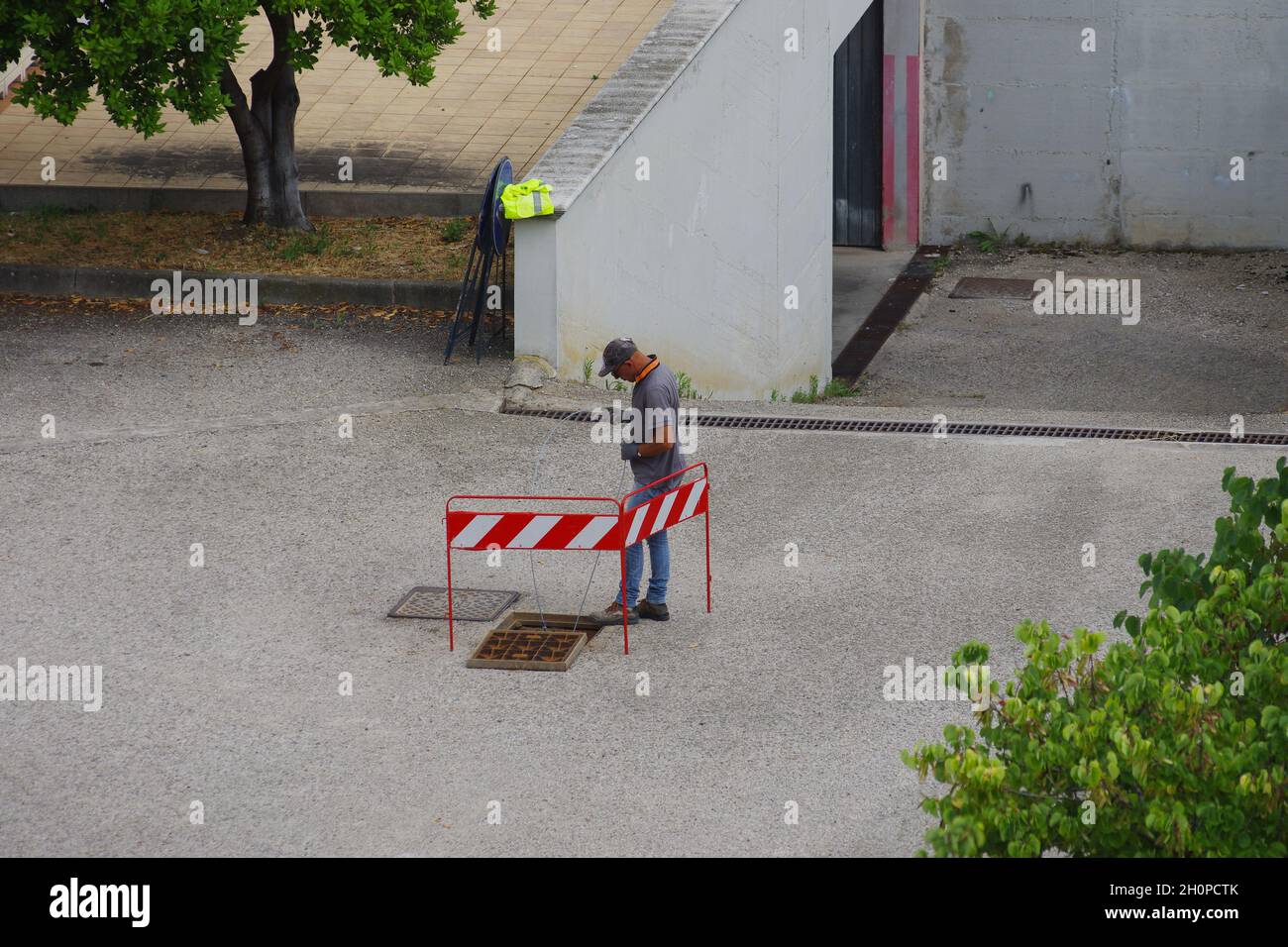 L'ouvrier pose les câbles à fibres optiques pour le câblage de la ville en utilisant les infrastructures existantes Banque D'Images