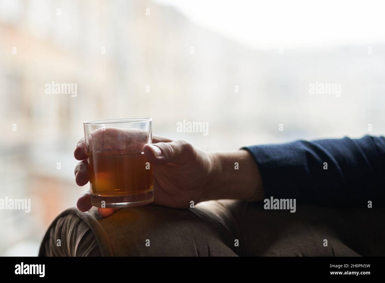 Gros plan de main d'un homme d'affaires réussi tenant un verre de whisky de scotch d'alcool tout en se relaxant dans une chaise Banque D'Images