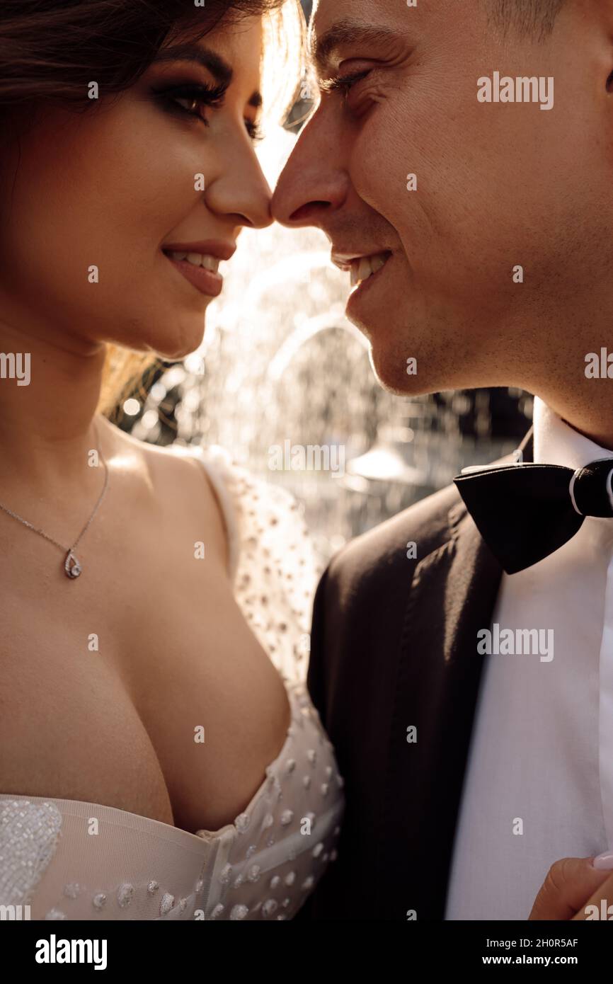 Photo de jeune couple amoureux embrassant dans les rayons du soleil couchant sur fond de paysage urbain avec fontaine, accroc les uns aux autres, mariage d Banque D'Images