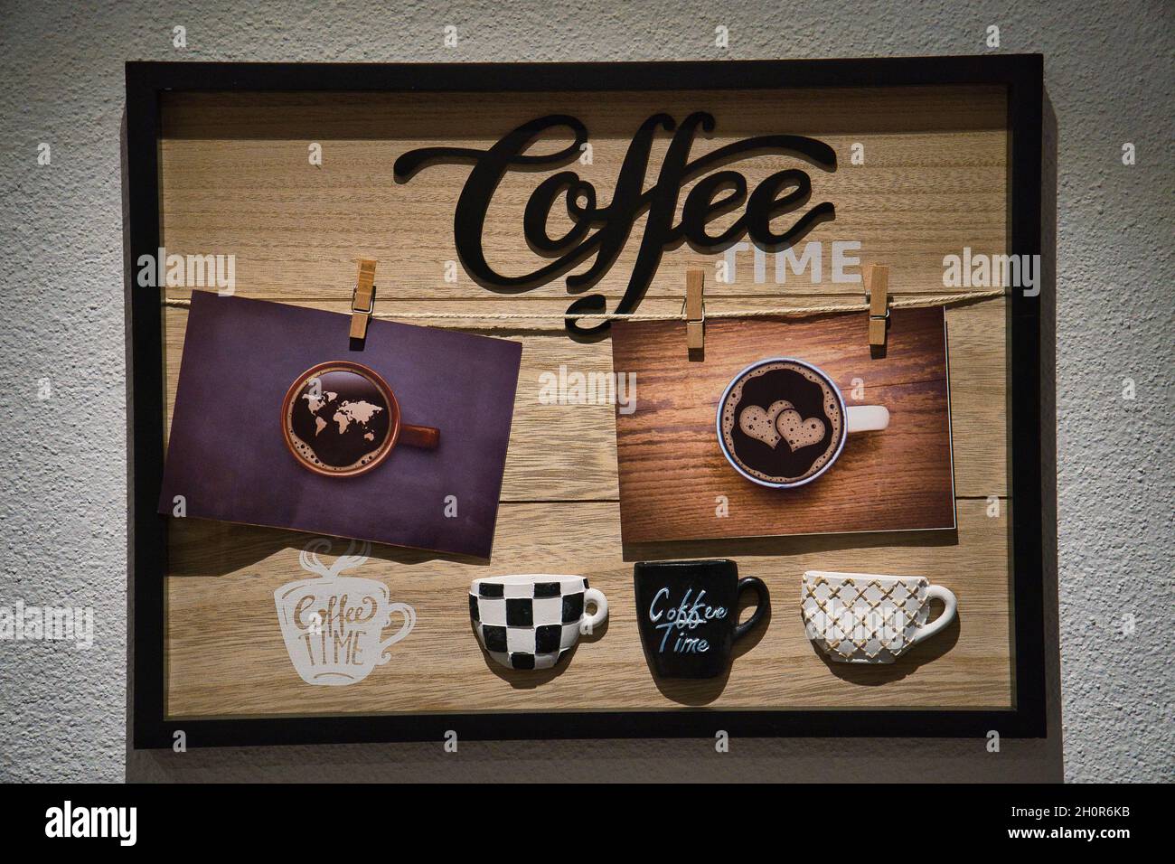 Photos d'une tasse de café accrochée à la corde avec des épingles sur une planche en bois avec un cadre noir Banque D'Images