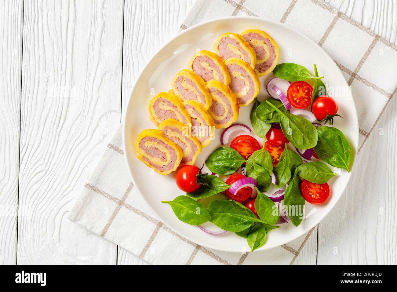 petits-déjeuners au jambon et au fromage hachés avec omelettes et salade d'oignons rouges aux épinards frais sur une assiette sur une table en bois blanc, vue horizontale depuis un Banque D'Images