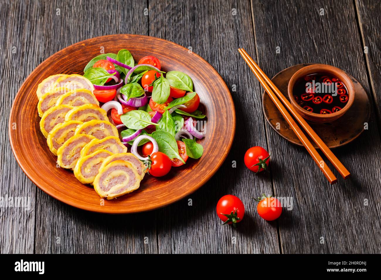 petit déjeuner au jambon et au fromage omelettes, pignons et salade d'oignons rouges aux épinards frais sur une assiette rustique sur une table en bois, vue horizontale fr Banque D'Images