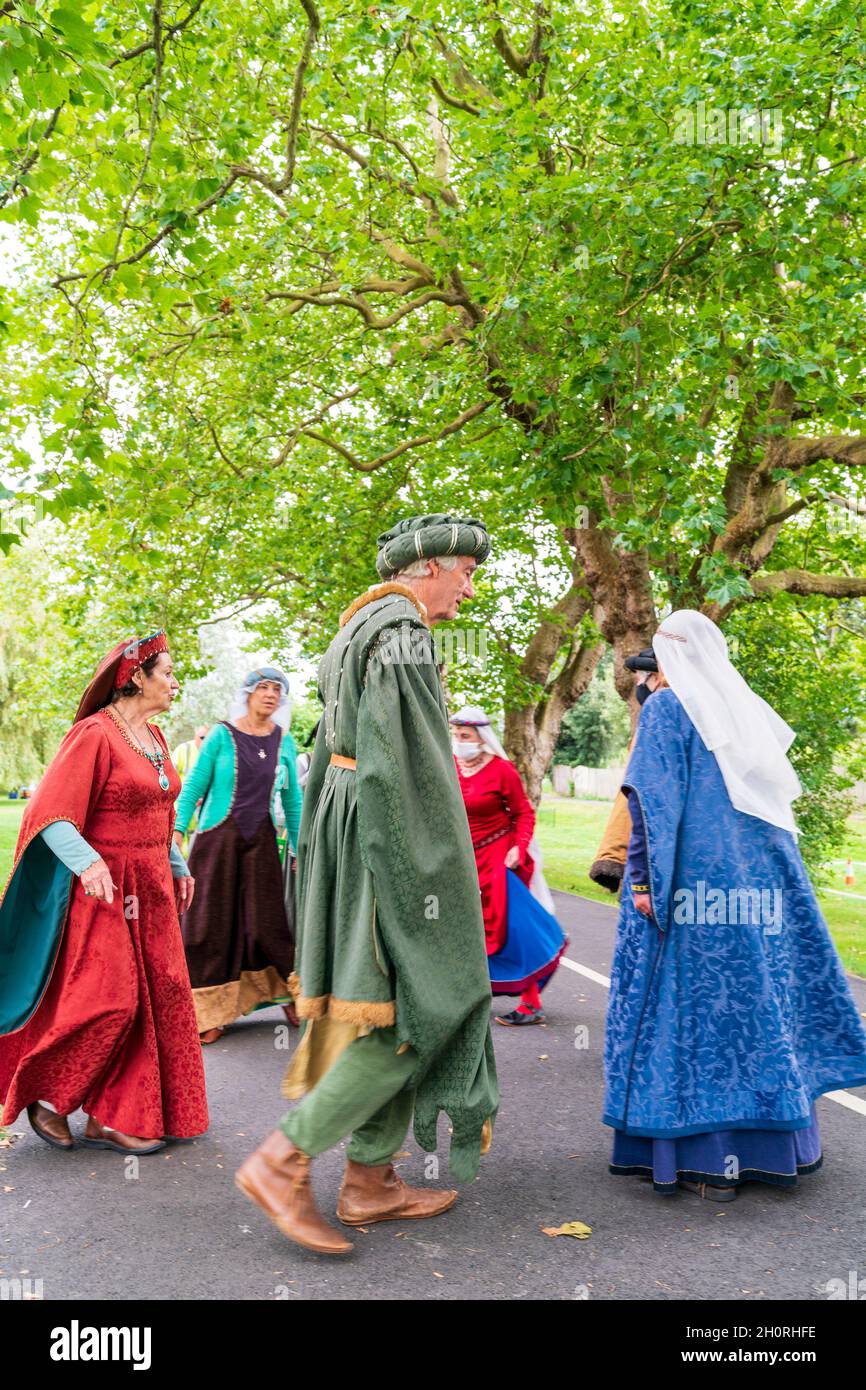 Groupe de réacteurs médiévaux dansant sur un sentier sous quelques arbres.Quatre femmes et deux hommes vêtus de costume médiéval coloré. Banque D'Images