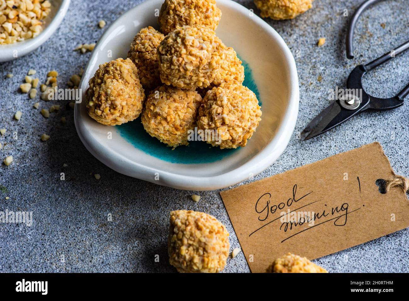 Des boules de bonbons maison en bonne santé enrobées de noix hachées à côté d'une étiquette du matin Banque D'Images