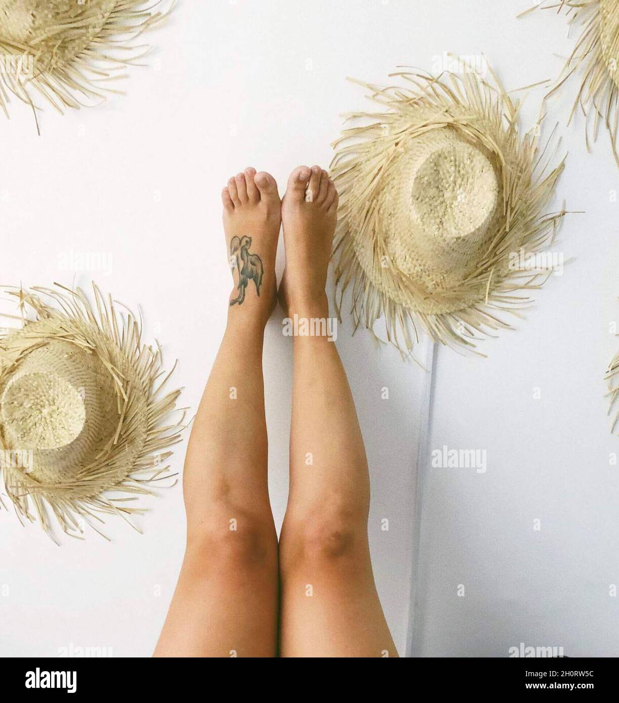 Les jambes de la femme contre un mur décoré de chapeaux de paille, Philippines Banque D'Images