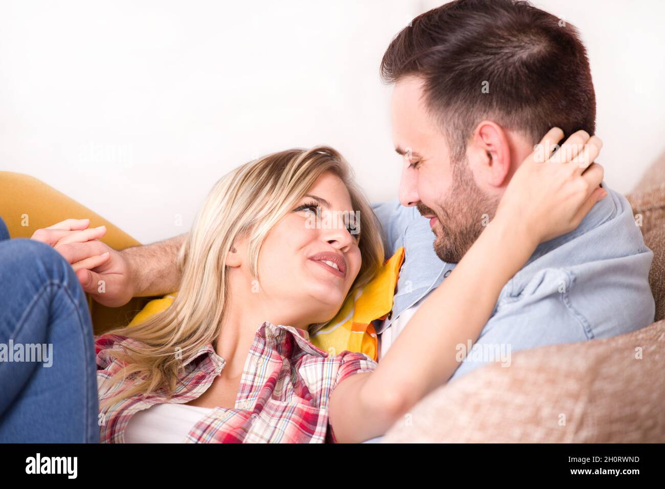 Jeune couple amoureux, ayant des moments intimes sur le canapé, embrassant et regardant l'un l'autre.Arrière-plan blanc Banque D'Images