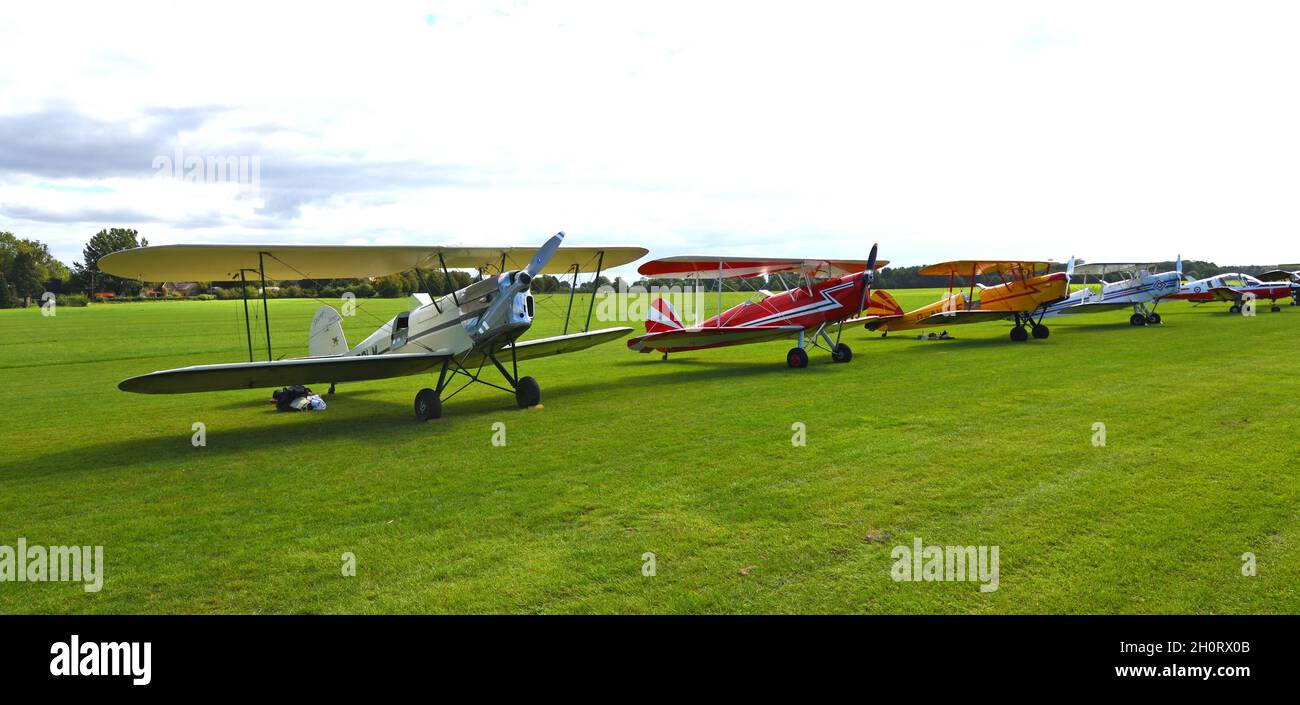 Quatre avions Vintage Stampé Biplane sur une piste d'atterrissage avec ciel bleu et nuages. Banque D'Images