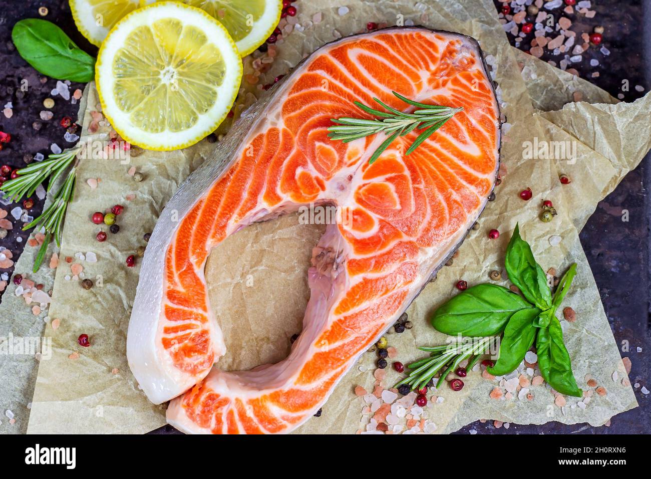 Des tranches de saumon rouge crues aux épices, au romarin et au citron dans la cuisine sur fond clair. Banque D'Images