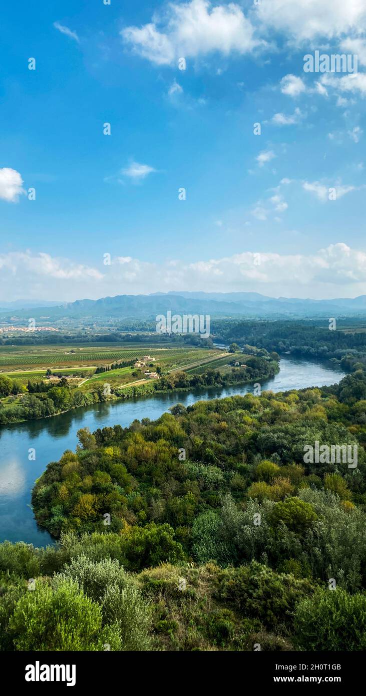 Le fleuve Ebro passant par Miravet, Espagne, avec la Serra de Cardo et les chaînes de montagnes d'Els ports en arrière-plan, dans un format vertical pour utiliser FO Banque D'Images