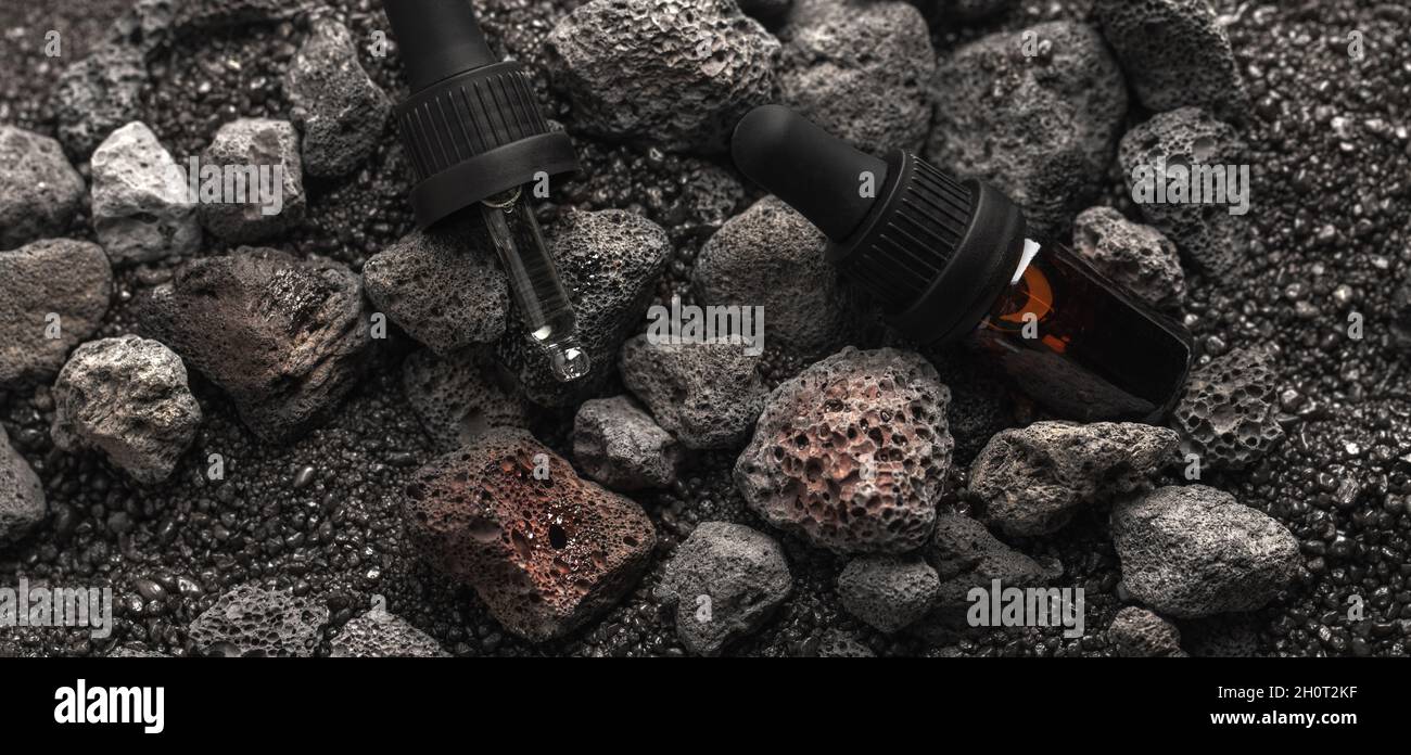 Huile essentielle pour l'aromathérapie et diffuseur minéral avec pierres volcaniques sur fond de sable noir.Aromathérapie, spa, soins de beauté et centre de bien-être Banque D'Images