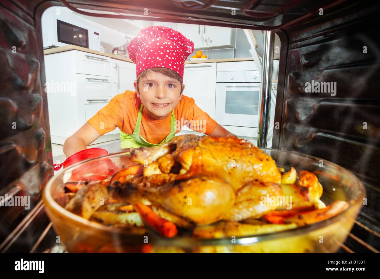 Cuisinière de garçon Prenez le gros repas de poulet du four Banque D'Images