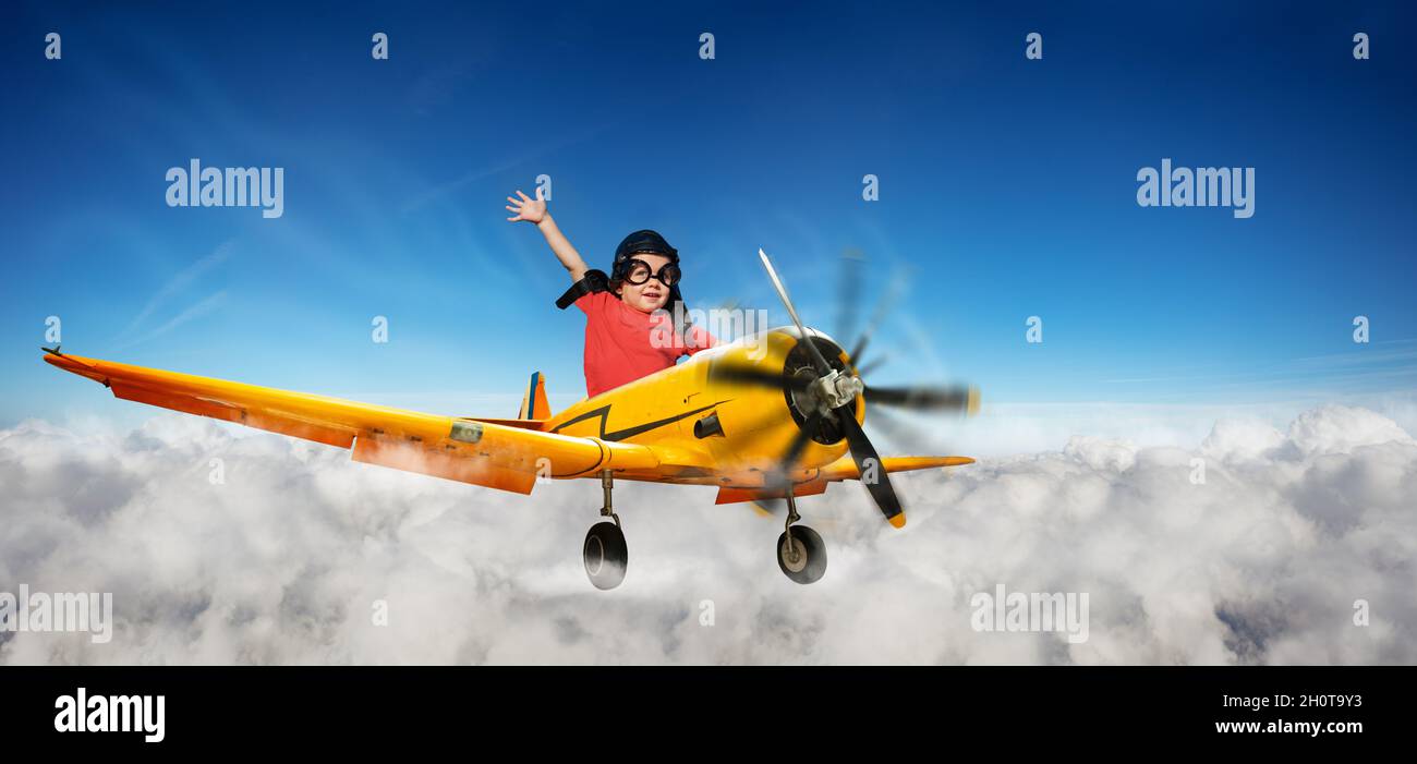 Garçon volant à bord d'un petit avion jaune dans le ciel Banque D'Images