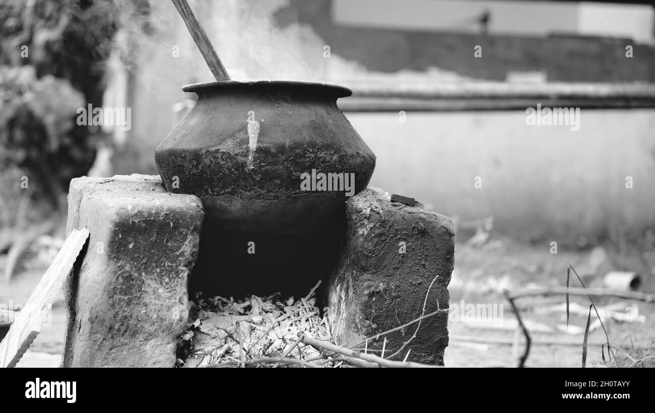 De l'eau ou quelque chose étant bouillie sur une poêle en aluminium maintenue sur un four de terre avec du bois comme combustible dans un village en Inde. Banque D'Images