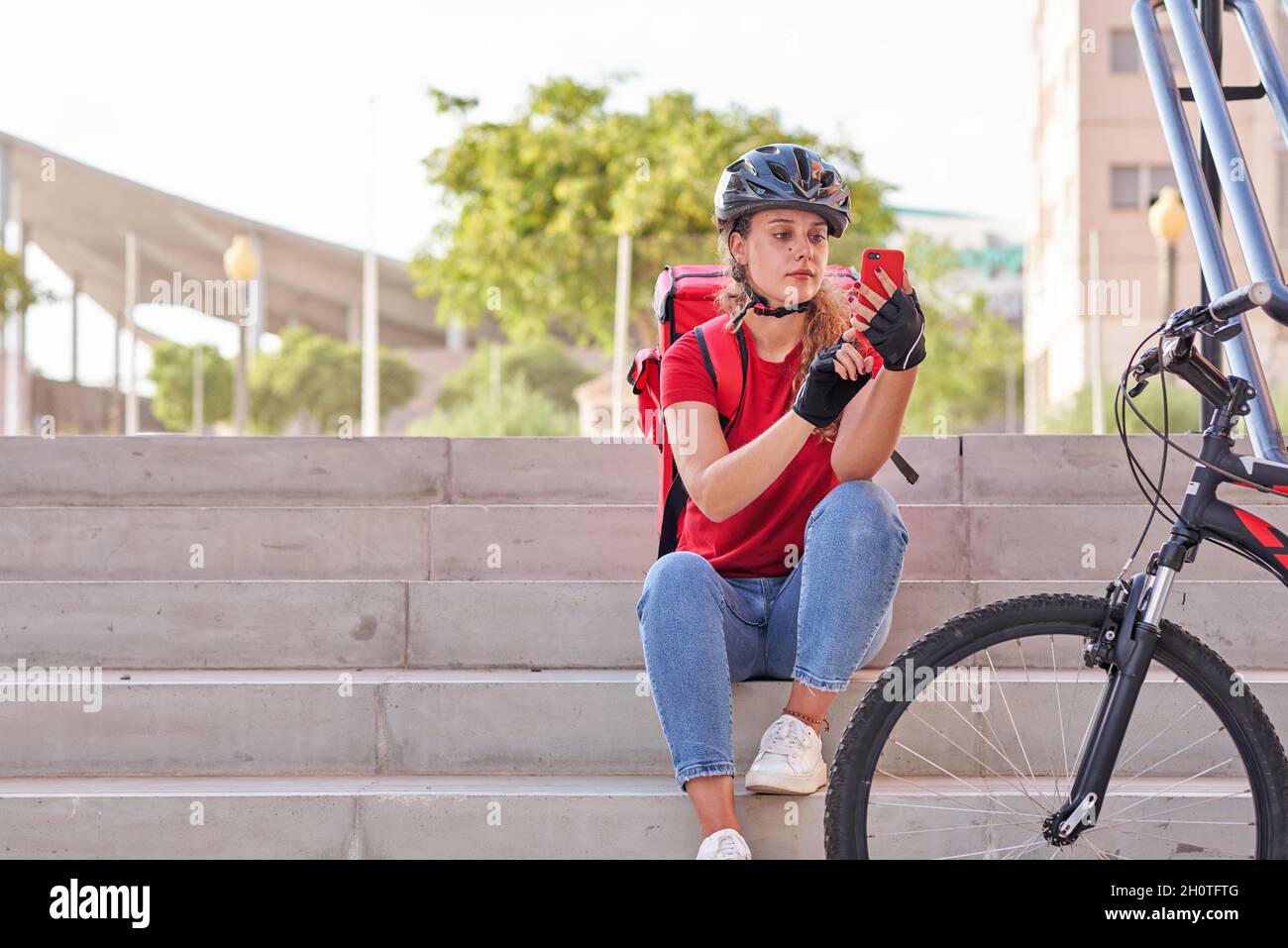 Une fille de livraison assise sur les escaliers en attendant la prochaine commande Banque D'Images