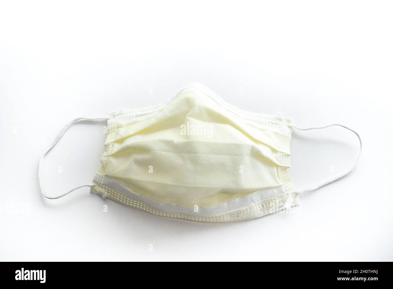 Gros plan d'un masque jaune utilisé pour les médecins ou d'un masque d'infirmière couvrant le visage regardant directement vers le bas isolé sur un fond blanc. Banque D'Images