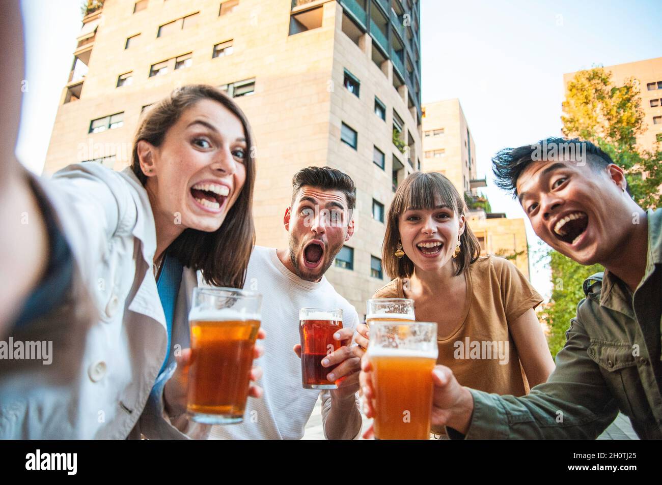 Des amis heureux qui font du selfie tout en buvant de la bière au pub en plein air de la ville - Friendship style de vie concept avec jeunes millénaires multiculturel peop Banque D'Images