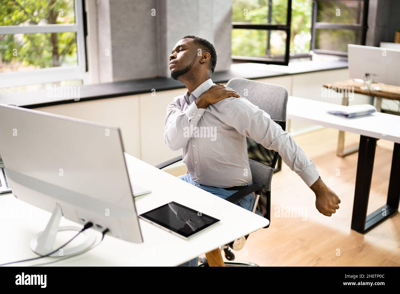 Employé s'étendant au bureau au travail Banque D'Images