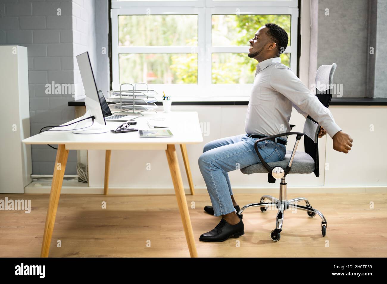Employé s'étendant au bureau au travail Banque D'Images